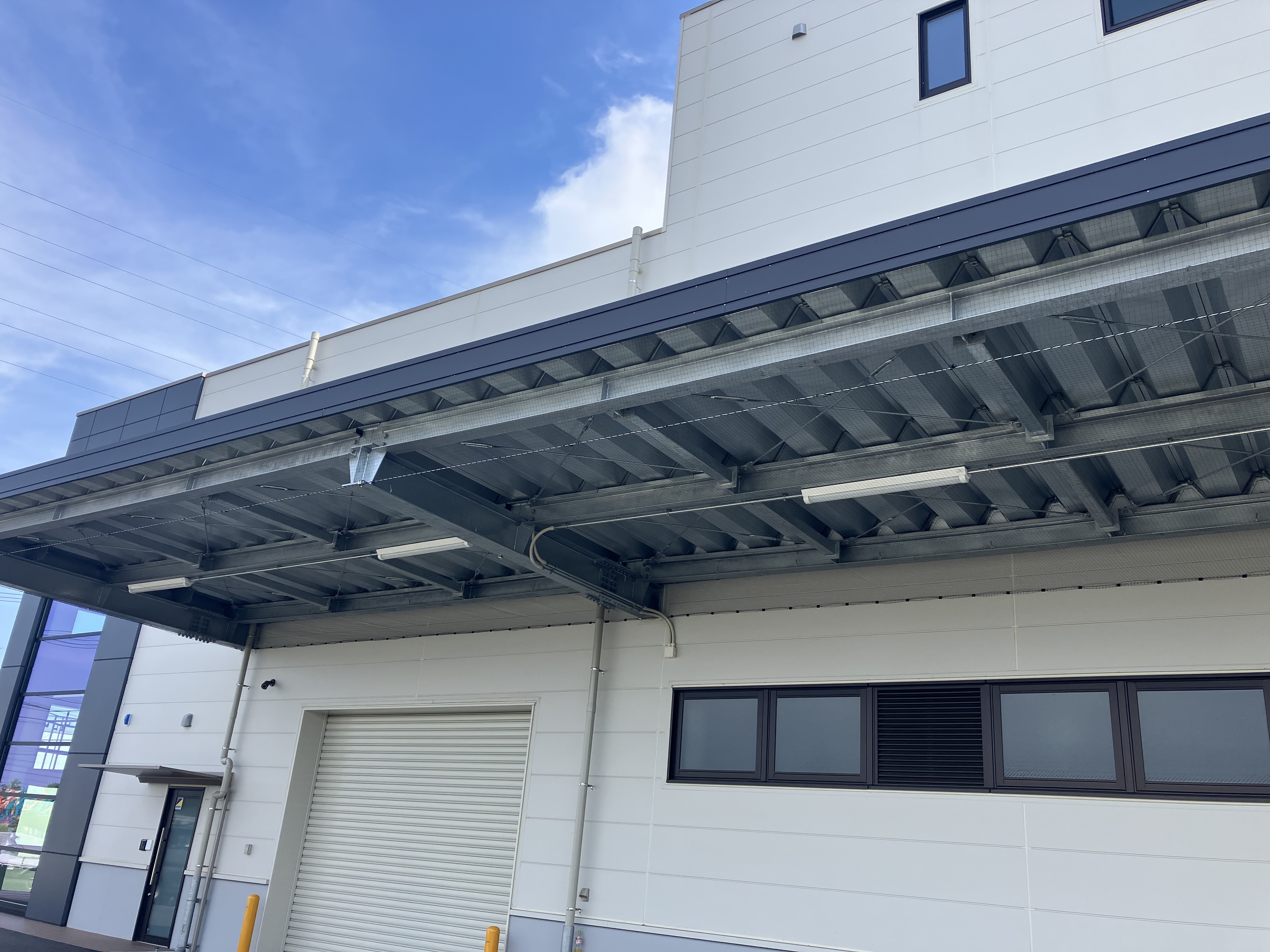 倉庫の鉄骨庇下に設置した鳩よけ防鳥ネットの施工事例 シャッター上部の鳥害対策