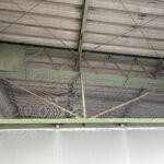 倉庫内の鉄骨梁の開口部に垂直に張ったグレーの防鳥ネット全景